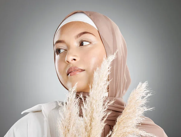 一位年轻美丽的穆斯林女子 戴着棕色头巾 手里拿着一棵与灰色背景隔离的扁豆小麦 头戴传统头巾 妆容端庄的女性阿拉伯男性 — 图库照片