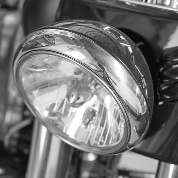 Closeup of a headlight on a motorbike. Motorcycle light with black and white filter. One light bulb on a sliver modern classic chrome coated motor vehicle. Clean, sleek chromium maintenance on a bike.