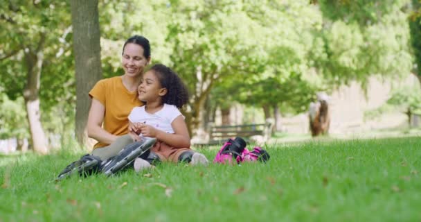 在阳光灿烂的日子里 快乐的母亲和可爱的养女在公园的草地上放松地聊天 在花园里 微笑着的女人和小女儿在一起 分享着一个深情的吻 — 图库视频影像