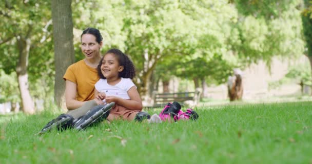 快乐可爱的妈妈和她可爱的小孩儿在公园的草地上休息和聊天 在一个家庭外出的日子里 在花园里 微笑着的女人和女儿粘合在一起 穿着溜冰鞋 — 图库视频影像