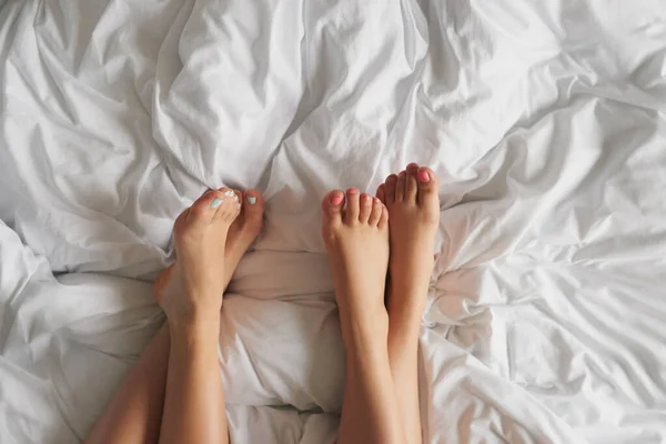 两个无法辨认的女人的双脚在家里的床上放松地在一起 拍摄的高角镜头 — 图库照片