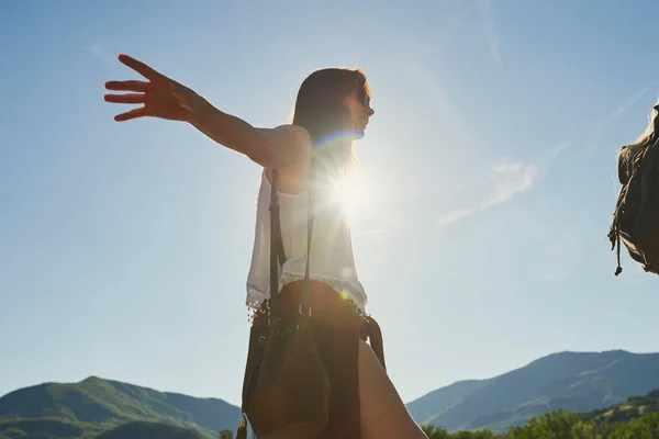 Carefree young woman balancing and walking during a hike in nature with a friend. Young woman enjoying a hike in nature in with a friend. Happy young woman balancing during hike in nature with friend.