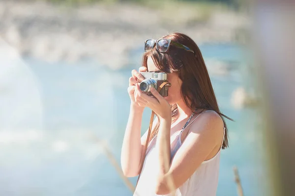 休暇中にデジタルカメラで自然の写真を撮る若い女性 川の自然風景を撮影するために彼女のデジタルカメラを使用して休日の冒険の若い女性 — ストック写真