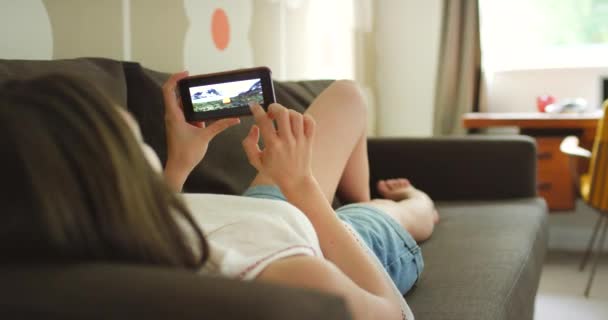 Woman Looking Photos Her Cellphone While Relaxing Her Couch – Stock-video