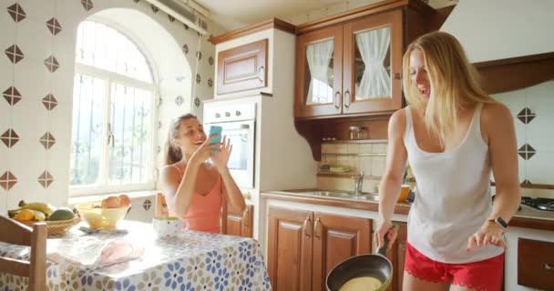 一个快乐的年轻女人用手机给她的朋友拍了一张翻着煎饼的照片 — 图库视频影像