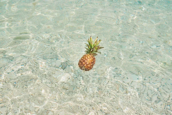 在蓝色热带海水中漂浮的异国情调菠萝水果象征健康有机饮食 — 图库照片