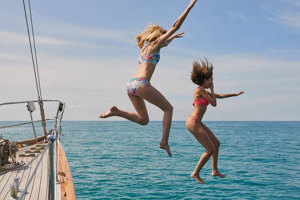 興奮した女性のボートから海で泳ぐジャンプします クルーズ中にボートから海で泳ぐ陽気な女性 — ストック写真