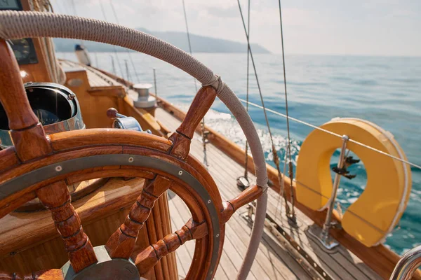 Closeup of wooden steering wheel on empty boat sailing the ocean. Closeup of empty boat deck with rigging cables wooden steering wheel sailing the ocean