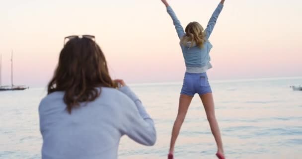Una Mujer Tomando Fotos Amigo Saltando Mientras Pasan Tiempo Playa — Vídeo de stock