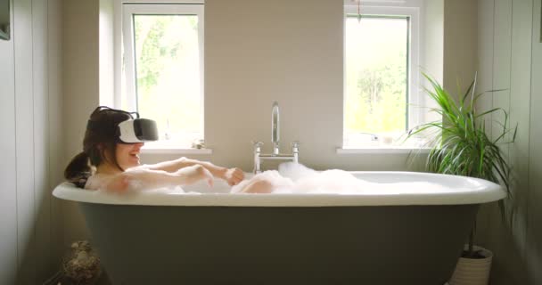 一个兴奋的女人一边在泡泡浴中使用Vr耳机一边挥手 — 图库视频影像