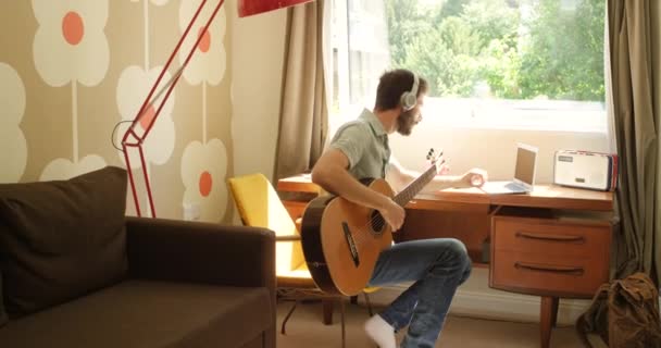 Content Young Man Listening Himself Play Guitar While Using His – Stock-video