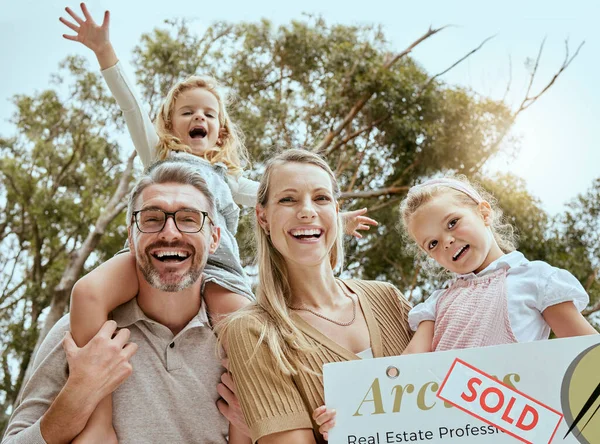Portrait of happy caucasian family holding a sold sign while relocating and moving into a new house. Smiling parents and kids secure homeowner loan for property real estate and home purchase.