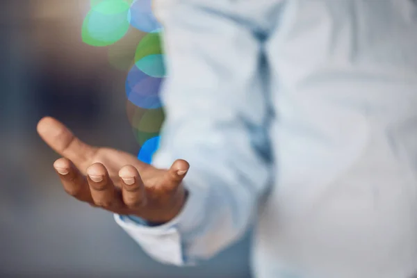 Closeup young african man standing with his hand out holding copyspace while working late at night in his office. African american business man endorsing, recommending or showing a product or advert.