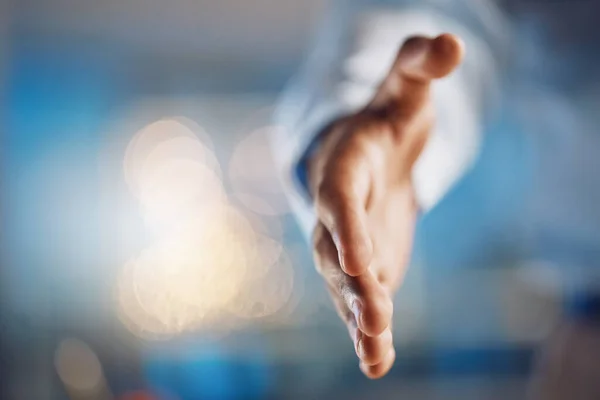 Closeup hand of african man gesturing for a handshake. African american business man standing with his hand out while working late night in office. Making a deal, agreement, merger or partnership.