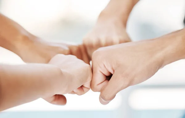 Closeup of diverse group of people making fists in a circle to express unity, support and solidarity. Hands of multiracial community greeting with fist bump in a huddle. Society joining together for