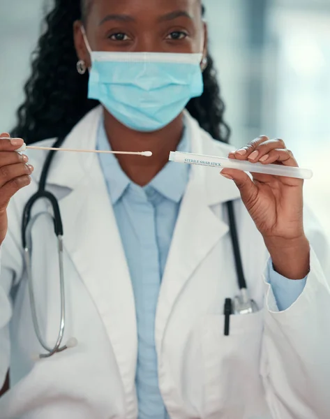 African american doctor wearing a covid mask. Young doctor holding a sterile swab stick. medical professional holding a corona virus test swab and sample. Healthcare professional in the hospital.