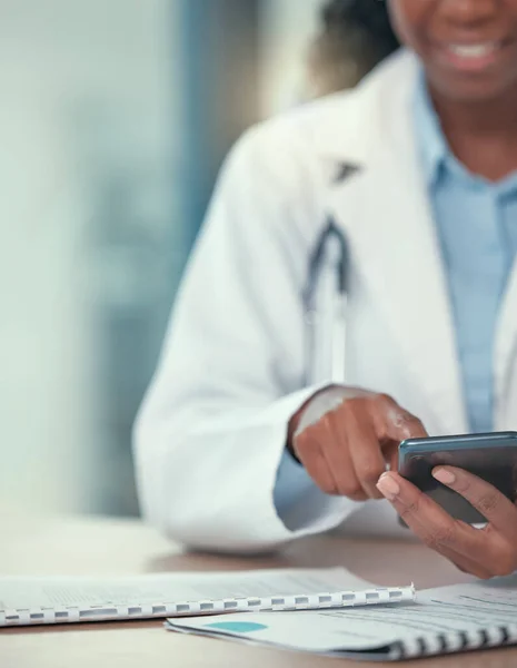 African american doctor using their smartphone. Medical professional sending a text on their cellphone. Closeup on hands of medical professional browsing an app online using a mobile phone.