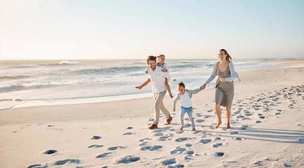 Happy family walking on the beach together. Young caucasian family relaxing together on the beach. Parents bonding with their children by the ocean. Mother and father walking with their children.
