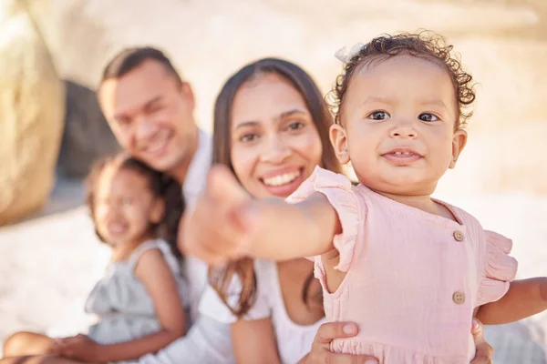 A happy mixed race family of four enjoying fresh air at the beach. Hispanic couple bonding with their daughters while having a picnic in a garden or park.