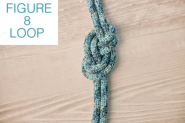 Above shot of hiking rope tied in a knot against a wooden background in studio. Figure 8 knot, A knot for every situation. Strong rope to secure safety while mountain climbing or doing extreme sports.
