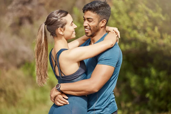 Affectionate young interracial couple taking a break from exercise and run outdoors. Loving man and woman hugging while motivating each other towards better health and fitness.