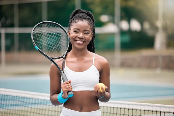 Smiling tennis player holding a ball. African american girl ready for her tennis match at the club. Young woman holding her tennis ball and racket on the court. Girl ready for tennis practice.