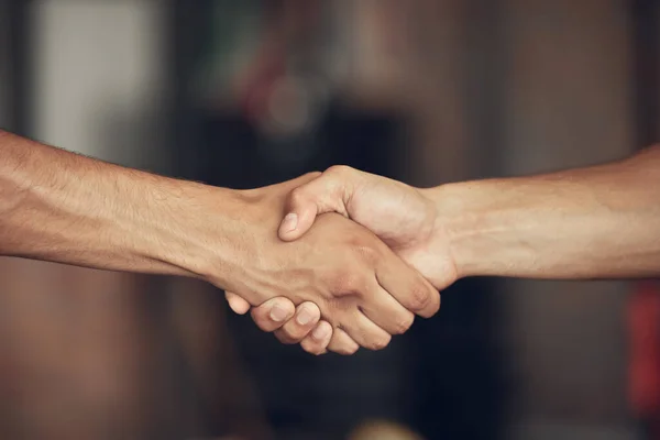Closeup on hands of athletes handshake in the gym. Two bodybuilders greeting before workout together. hands of fit men collaborate before exercise. Athletes saying hello in the gym.