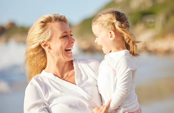 Closeup of a caucasian girl laughing while enjoying a day out with her mother at the beach. Mom and daughter enjoying a summer vacation by the sea. Enjoying family time while on holiday.