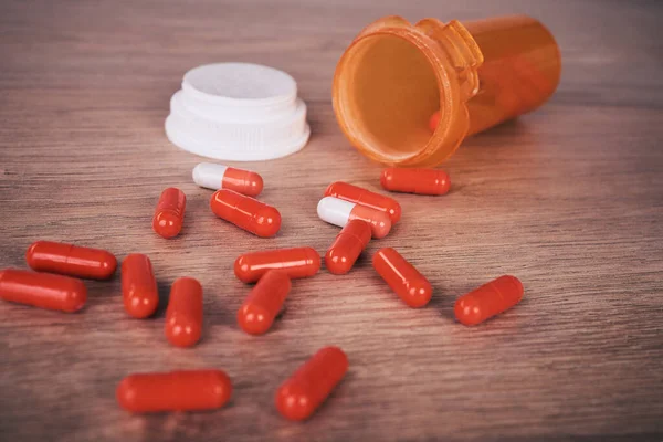 An open orange of brightly coloured pills spilled onto a wooden table. Vitamin supplements are a good way to maintain your health. Chronic or prescription medication are usually covered by medical aid