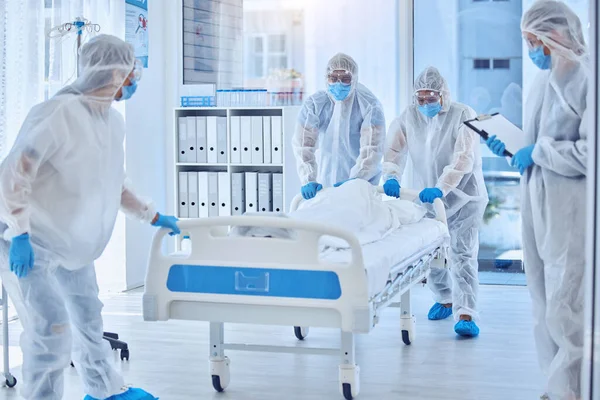 Medical science team moving hospital bed. Biohazard team in hazmat suits for protection in pandemic. Biologist team collecting a dead body from hospital. Csi team moving hospital bed with dead body.