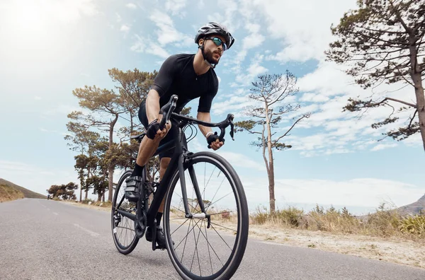 一个年轻的运动员在外面骑车 男子骑自行车在风景秀丽的山路上锻炼时 身材匀称 头戴安全帽 戴着眼镜 — 图库照片