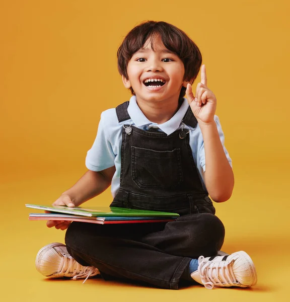 オレンジ色の背景を読みながら床に座ってかわいいアジアの少年の肖像画 教育に焦点を当てながら 幸せと内容 アイデアを持つかわいい子供 — ストック写真
