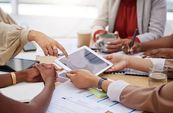 Diverse group of unknown business women using a digital tablet for a brainstorm meeting in the office. Professional team of colleagues using technology and paperwork while planning marketing strategy.