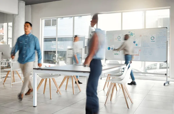 Group of diverse businesspeople walking around in a busy office at work. Business professionals rushing while working together in an office. Four colleagues getting work done in an office.