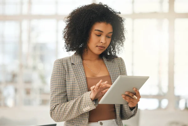 Young businesswoman using a digital tablet. Focused designer standing in her agency. Creative entrepreneur working on a wireless device. Young architect using an online app on her wireless tablet