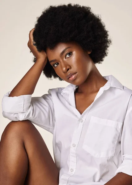 Studio portrait of a young stunning African American woman with a beautiful afro. Confident black female model showing her smooth complexion and natural beauty while posing against a grey background.