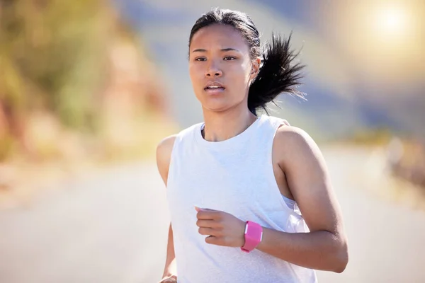 Active mixed race young woman running for exercise outdoors. Athlete jogging for a refreshing cardio training workout in the morning. Determined to build endurance to reach fitness and wellness goals.