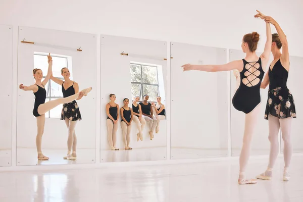 Young woman dance instructor teaching a ballet class to a group of a children in her studio. Ballerina teacher working with girl students, preparing for their recital, performance or upcoming show.