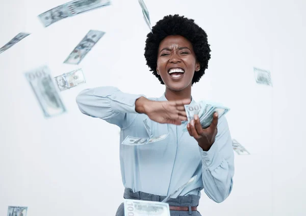 Mature african american businesswoman with an afro looking happy while throwing money around against a white background. Success, finance and celebration