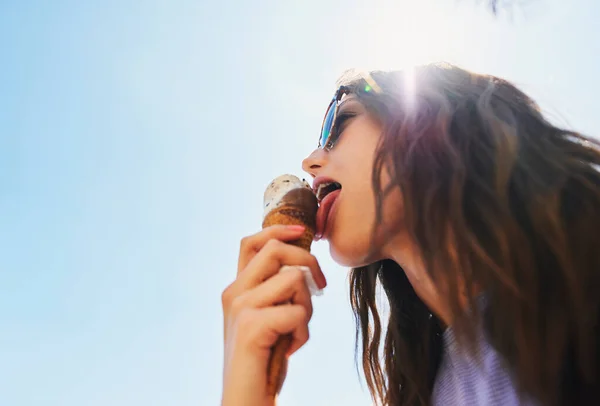 Woman eating ice cream on summer vacation. Low angle of girl having treat on beach.