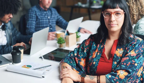 Portrait of a young powerful businesswoman in a meeting with her staff. A focused young businesswoman sitting at her desk before a meeting with a diverse group of staff