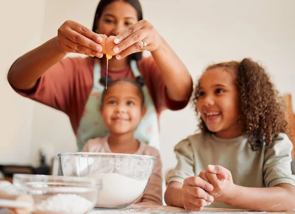 Females only, happy mixed race family of three cooking in a messy kitchen together. Loving black single parent bonding with her daughters while teaching them domestic skills at home.
