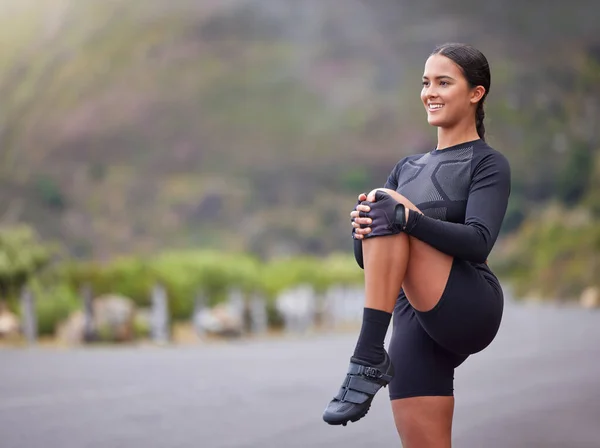 Active and fit young mixed race woman stretching her leg during outdoor exercise. Smiling, toned hispanic athlete getting ready to run in the morning. Routine sports and physical activity are healthy.