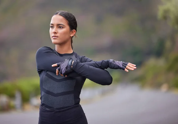 Young mixed race hispanic female stretching before a run outside in nature. Exercise is good for your health and wellbeing. Stretching is important to prevent injury and sore muscles.