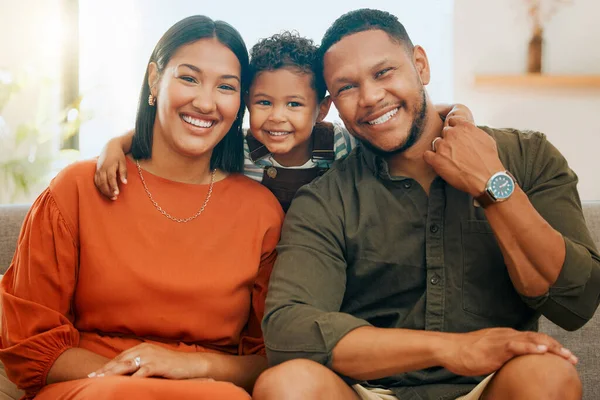 A happy mixed race family of three relaxing in the lounge together. Loving black family bonding with their son while sitting on the sofa at home.