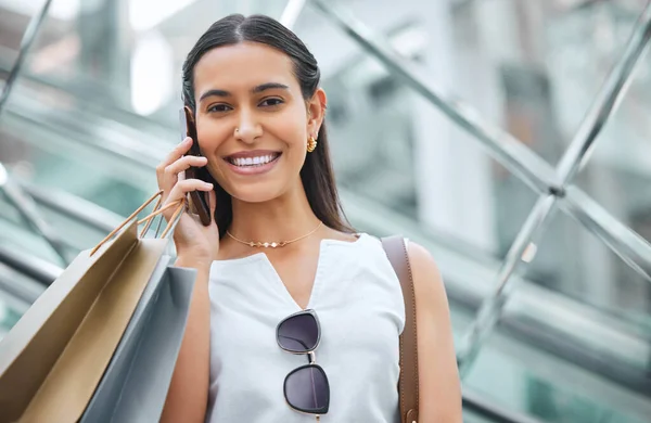 Portrait of a woman smiling while staying connected with a cellphone while out shopping. Trendy female on a call telling friends about a sale or discount at a mall. Enjoying the weekend with retail