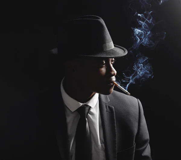 Mladý Afroameričan Který Vypadá Vážně Zatímco Kouří Cigaretu Černém Pozadí — Stock fotografie