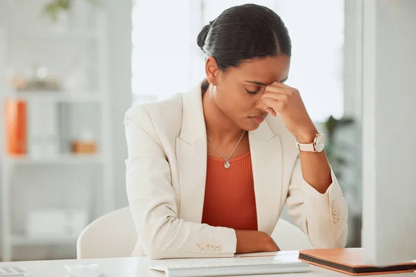 One anxious young hispanic business woman suffering with a headache while working on a computer in an office. Entrepreneur feeling overworked, tired and anxious about deadlines. Mentally frustrated