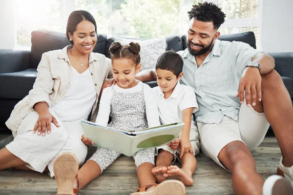 Mixed race family reading a book together on the floor at home. Hispanic mother and father teaching their little son and daughter how to read. Brother and sister learning to read with their parents.