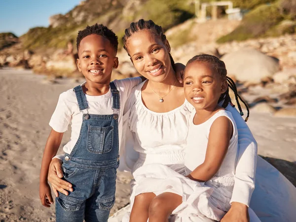 Portrait of a happy loving young african american mother at the beach with her two children. Little girl and boy enjoying vacation by the sea with their mom.